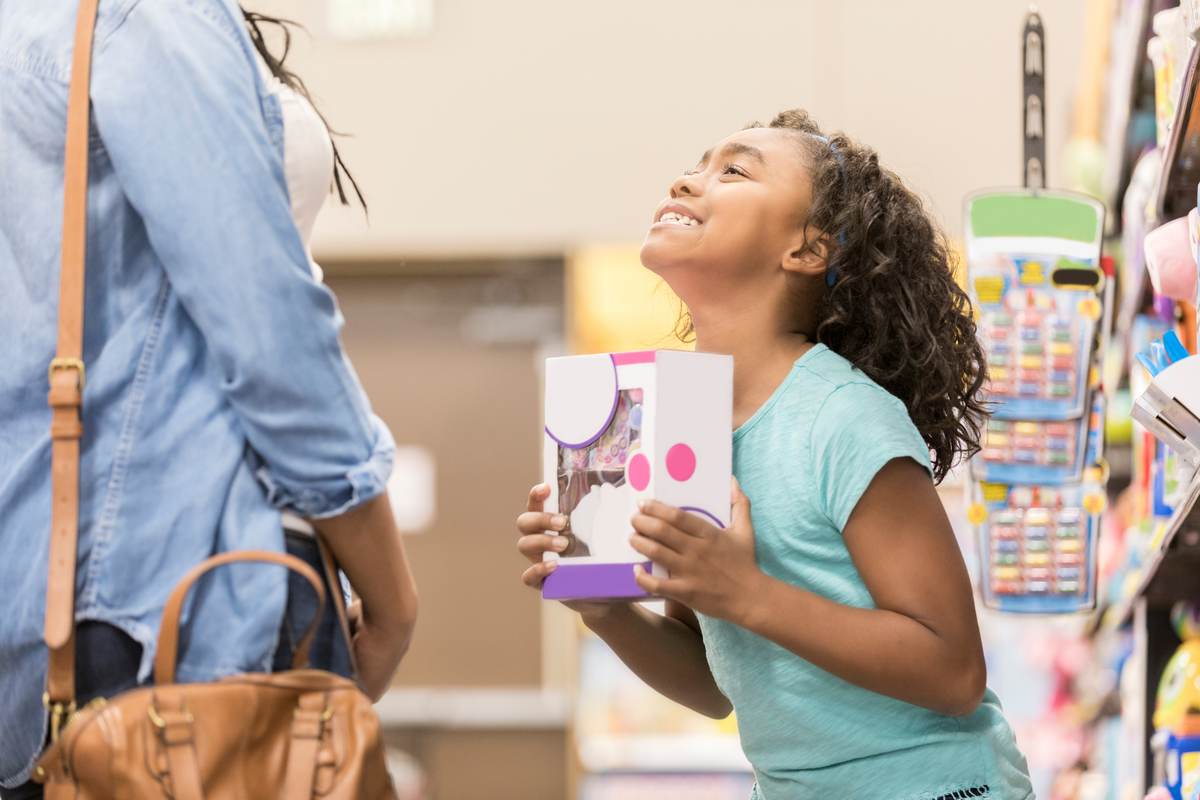 A little girl begs her mom to buy her a toy.